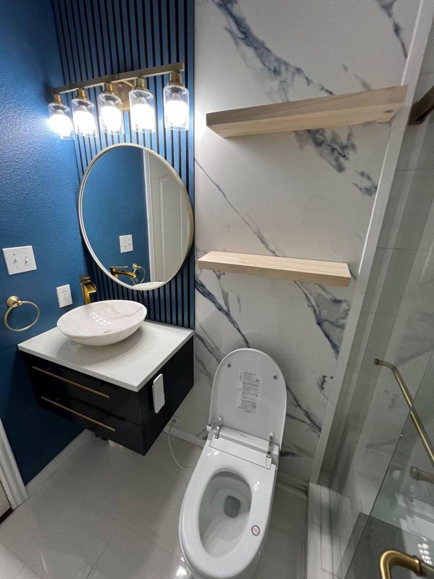 Finished vanity wall with navy slats, round gold mirror and vessel sink