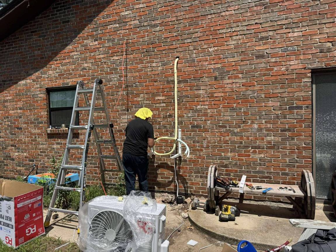 Technician mounting brackets and running the line set on a brick wall